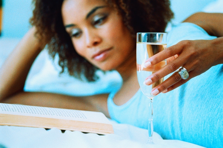 African American woman drinking wine reading