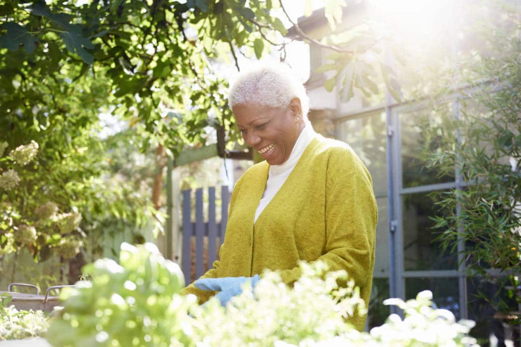 senior woman with pot plants in garden.