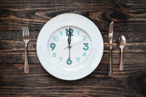 Twelve hour intermittent fasting time concept with clock on plate.