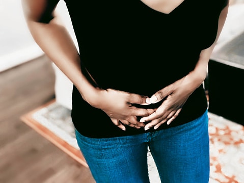Midsection of unrecognizable black woman suffering pelvic pain from adenomyosis, endometriosis, fibroids, ovarian cysts, pelvic inflammatory disease or other cause
