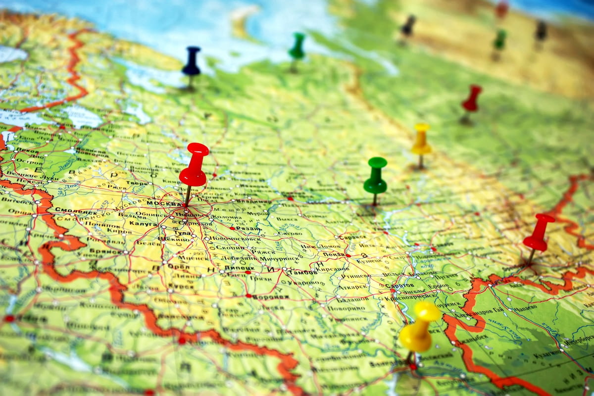 A close-up of a map of Russia with several colorful pushpins, including a red one marking Moscow, indicating travel plans or locations.